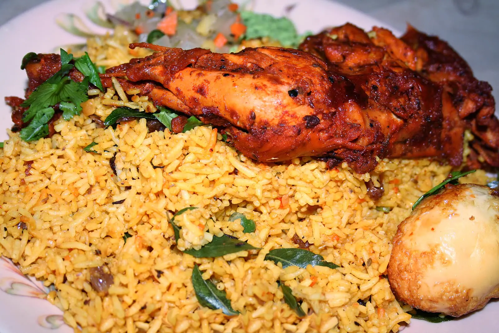 Plate of chicken biryani with an egg and herbs