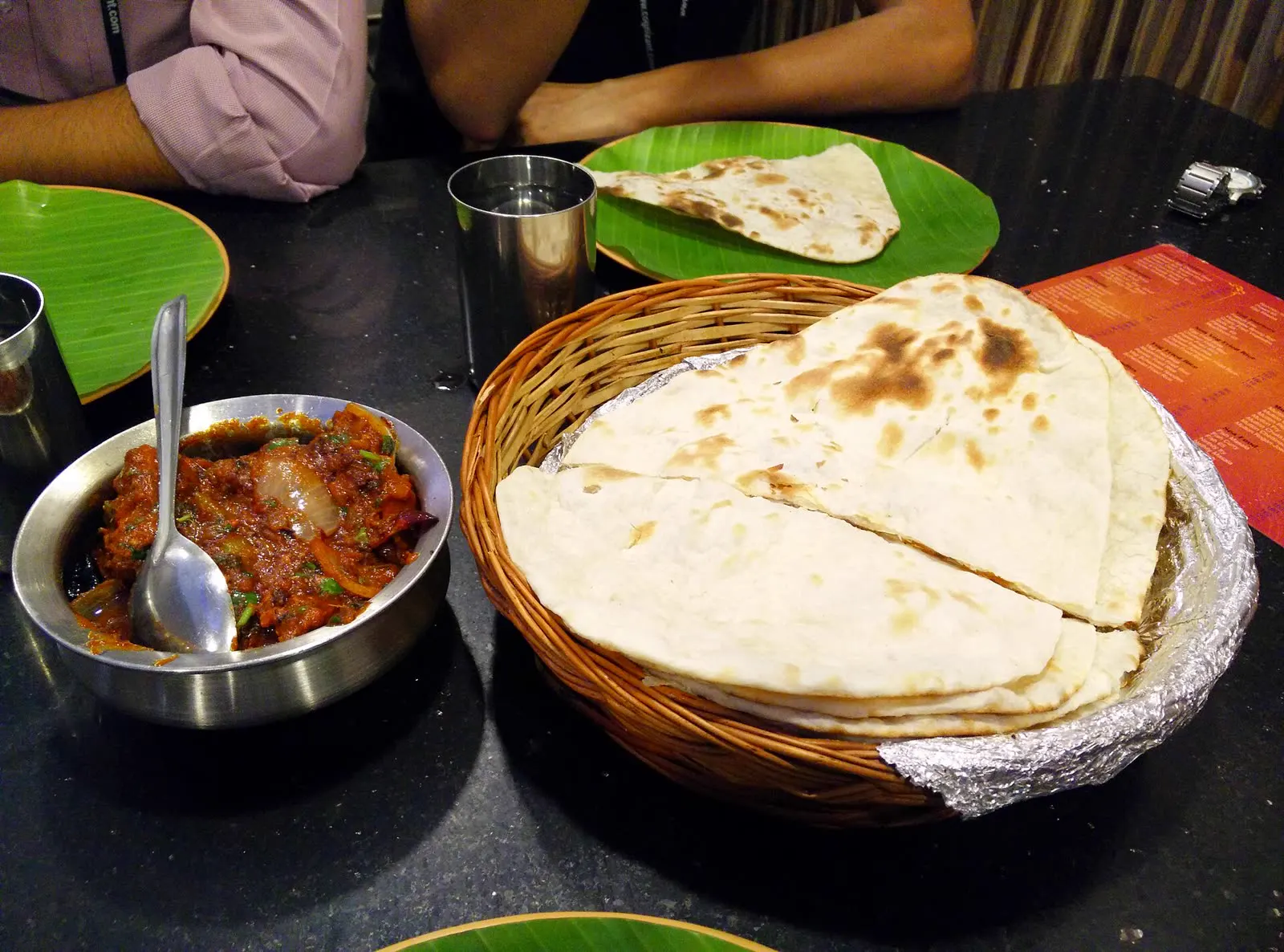 Chicken kadhai and a basket of naan on a dining table